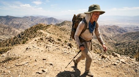 What to wear hiking in summer — a UPF sun hoodie and wide-brim hat on an exposed trail